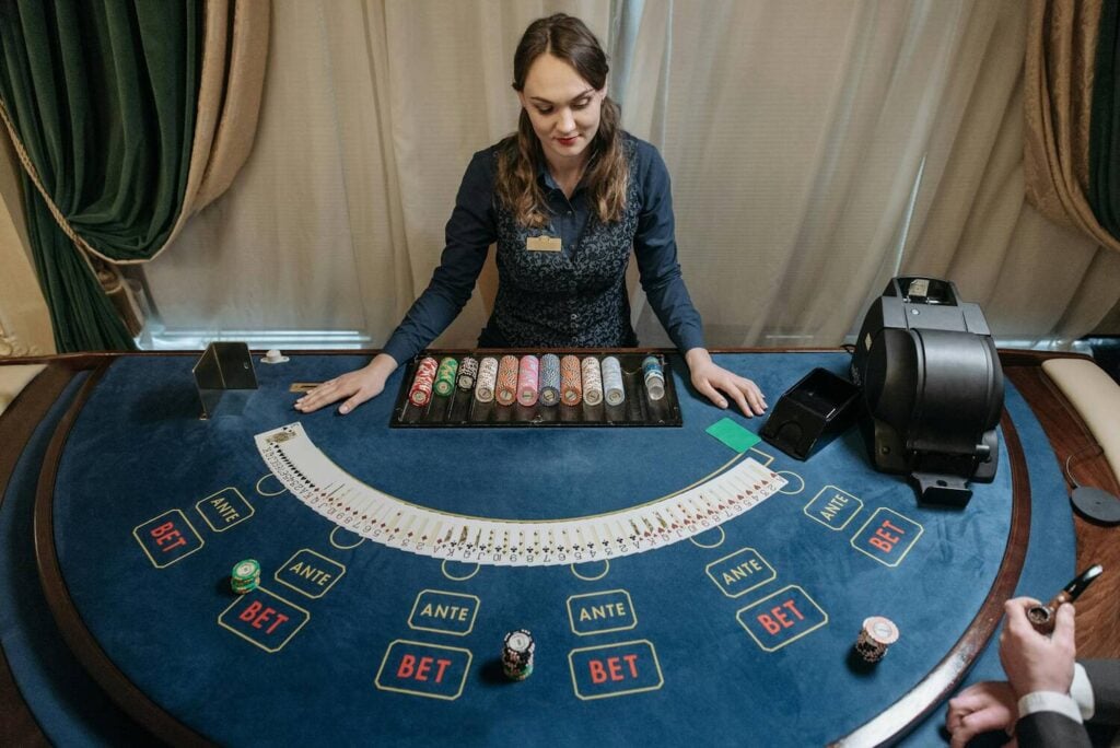 Casino dealer managing a card table with chips and betting layout
