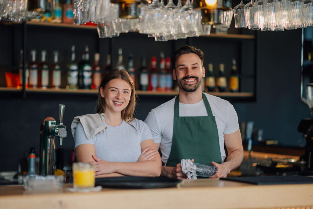 Two bar staff smiling behind the counter