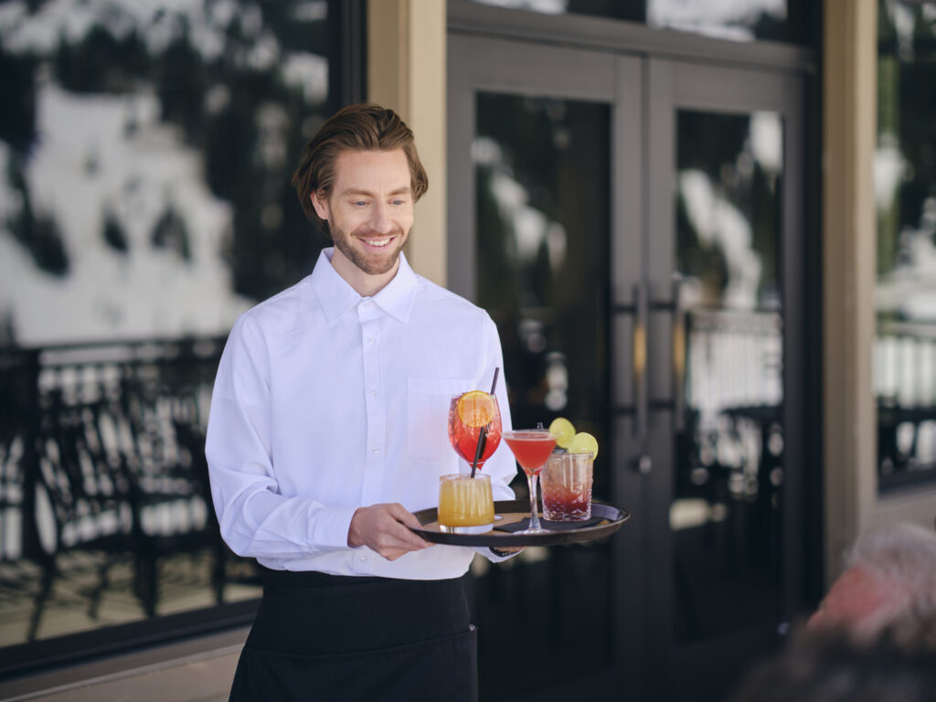 A food service employee serving cocktails at a luxury ski resort.