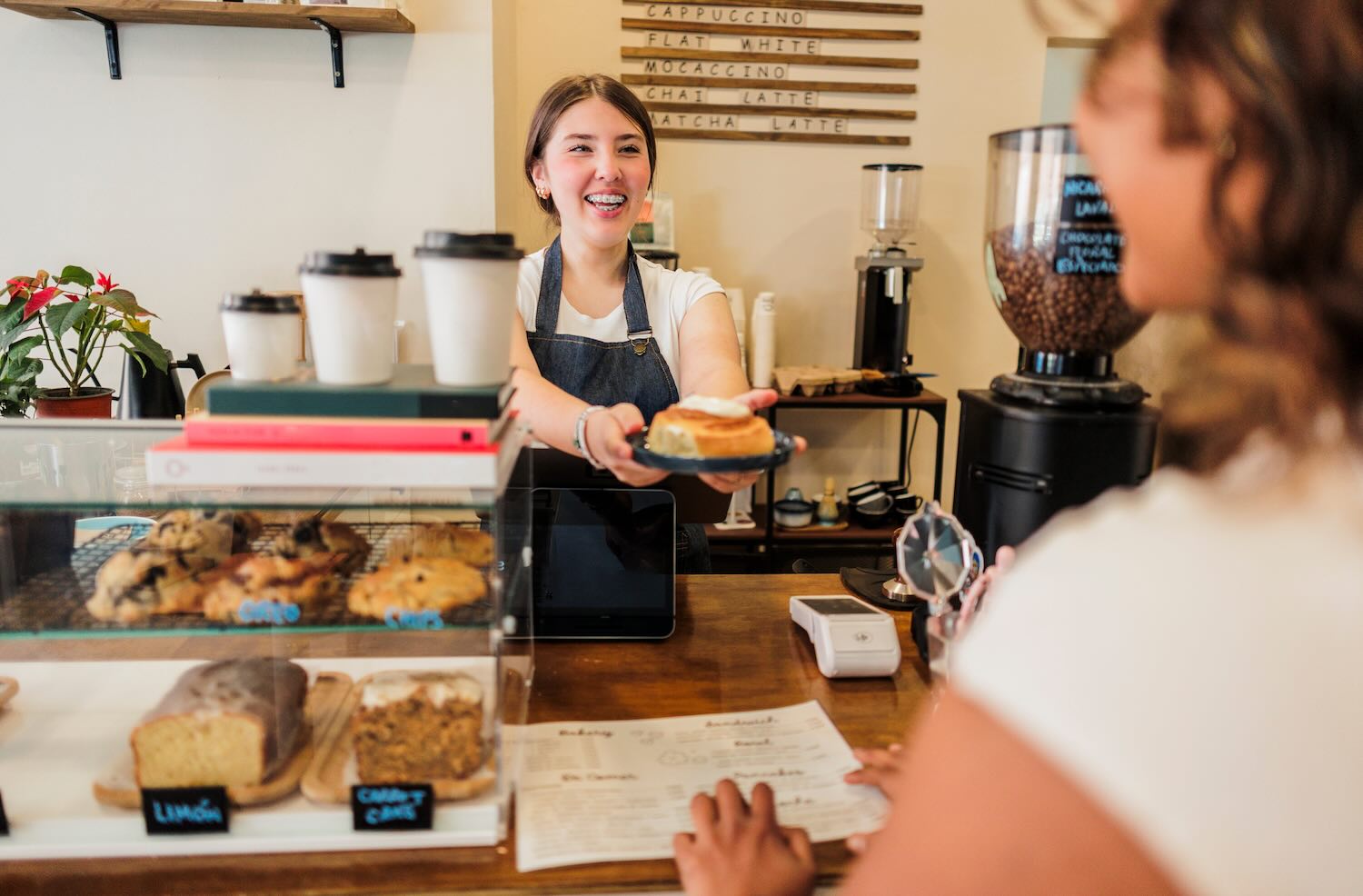 woman barista serving a cinnamon roll